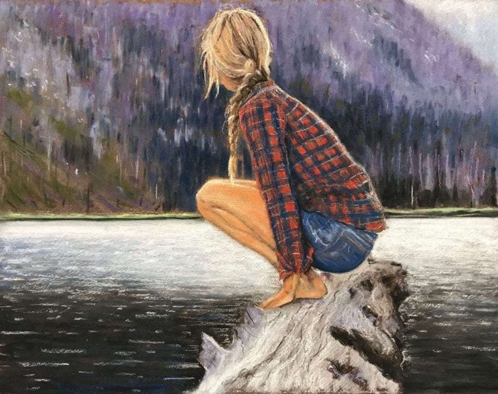 A blonde haired women in a lumberjack shirt, balanced on a large piece of driftwood, looking out in the steep sided lake.