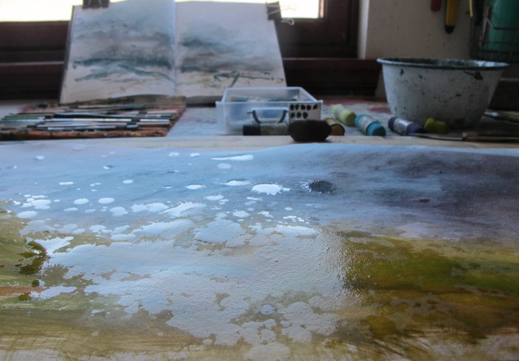 Libby puts spots of water onto the surface of the painting before working them into the paper with a brush.