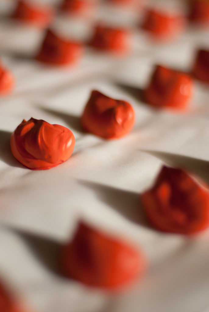 Red dollops of wet pigments lined out on blotting paper.