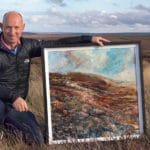 Robert Dutton out on the moors, posing by one of his beautiful paintings.
