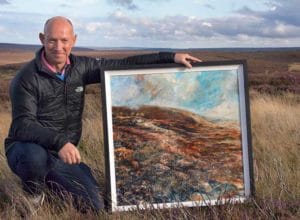 Robert Dutton out on the moors, posing by one of his beautiful paintings.