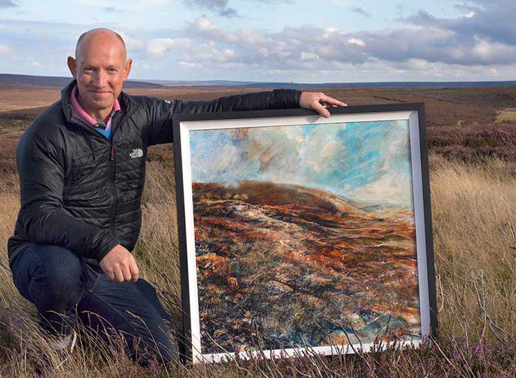 Robert Dutton out on the moors, posing by one of his beautiful paintings.