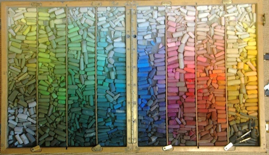Huge collection of soft pastels, neatly arranged by colour.