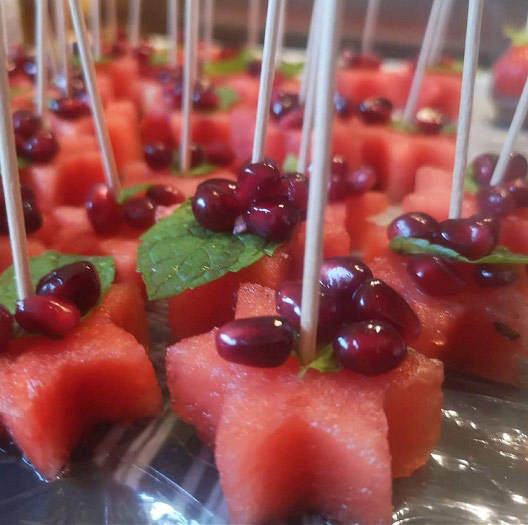 Watermelon with pomegranate  seed nibbles on cocktail sticks.
