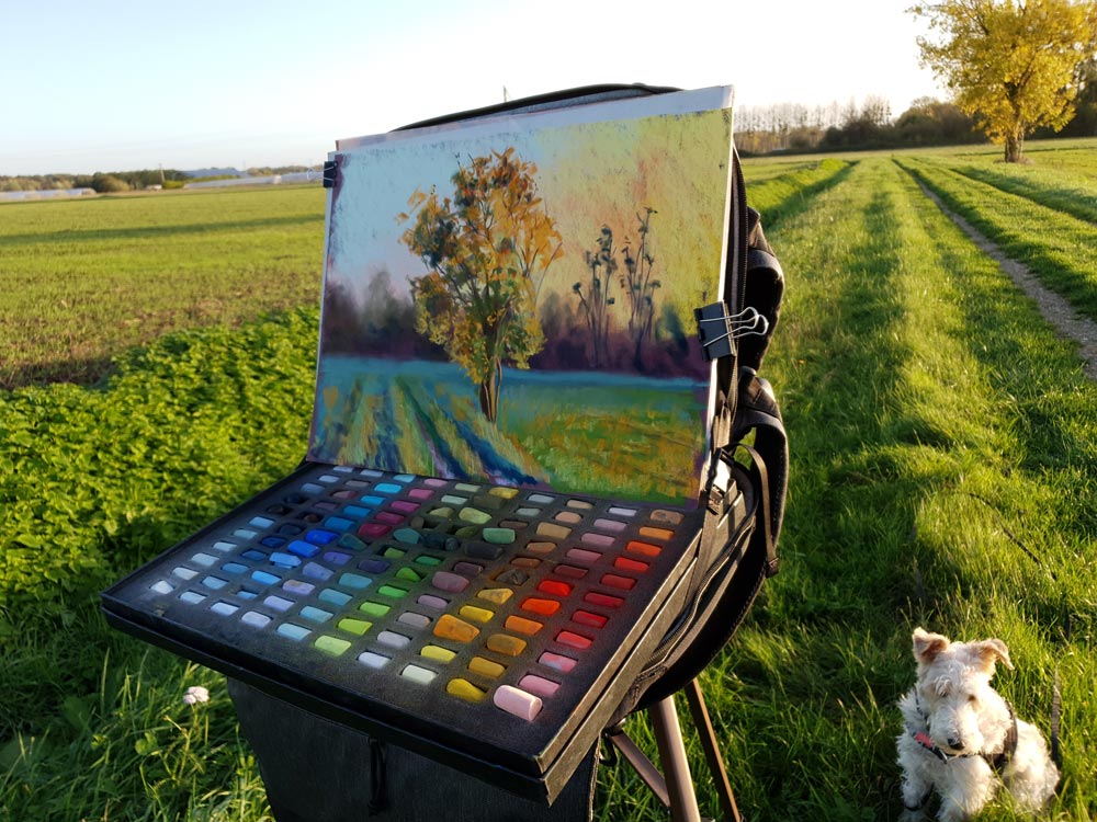 Cindy's painting on an easel in a field.