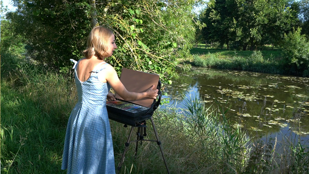Photo of Cindy painting by a river.