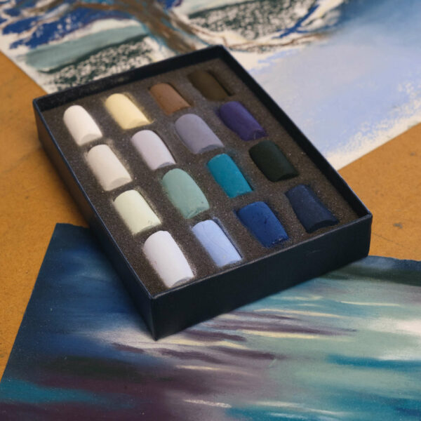 An open box of Frosty Winter's Day 16 Half Stick set of Soft Pastels, sitting next to a piece of artwork created with the set.