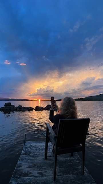 Lyn Asselta take a photo of the sunset across the bay.