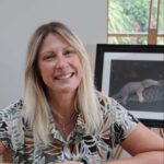 Profile photo of Meral Altilar, sitting in her studio in front of one of her works.