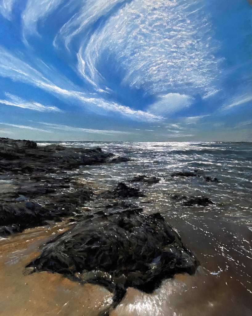 Soft pastel painting depicting a rocky outcrop into the sea, with blue sky and light swirling cloud.