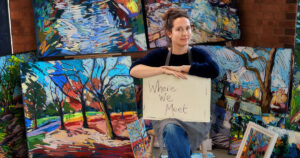Amy Shuckburgh sits amongst her artwork for the 'Where we meet' exhibition.